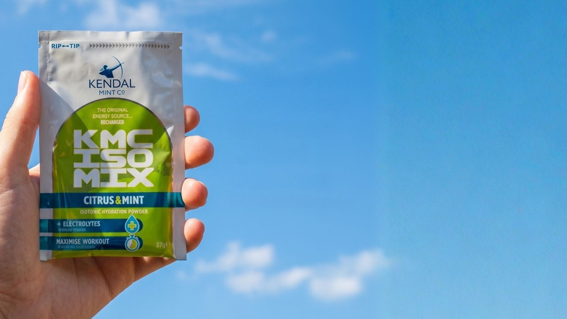 Hand holding a KMC ISO Mix packet against a blue sky